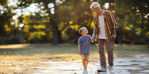 Grandfather and grandson walking together in a park
