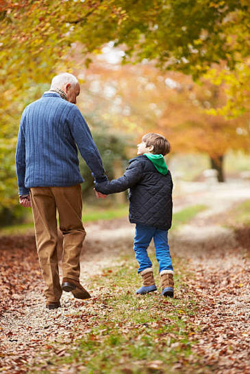 Grandfather and grandson walking on an autumn path